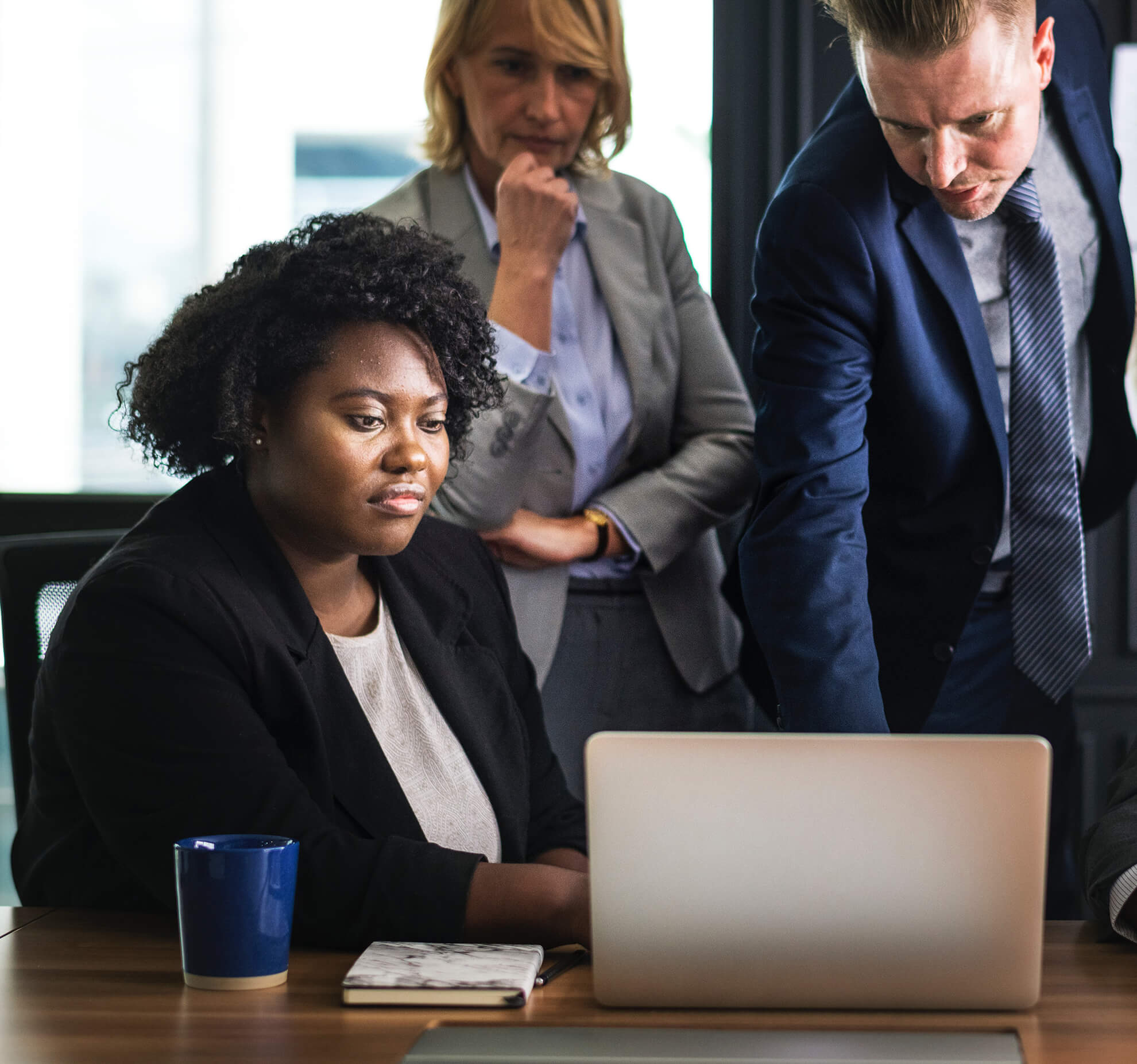 three business professionals gathered around a laptop